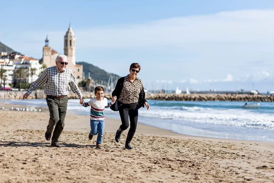 elderly couple running on beach in Italy with their grandson arm-in-arm